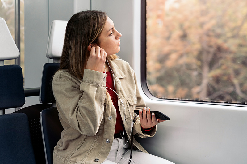 Gestigerte Kapazität mit 6G: Frau im Zug mit Handy